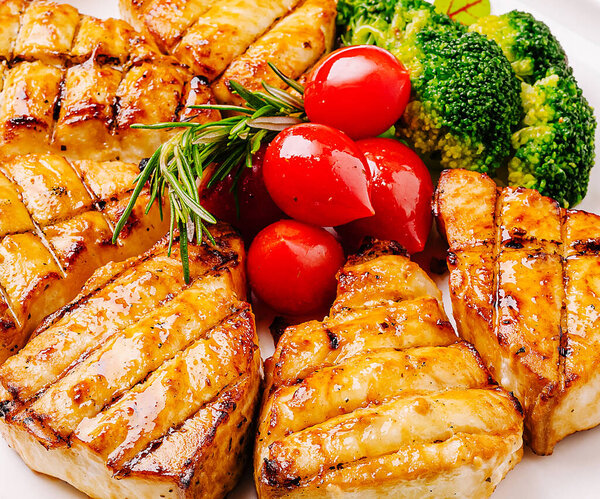 Juicy grilled salmon is arranged on a plate alongside fresh broccoli and vibrant cherry tomatoes, creating a colorful and healthy meal perfect for any occasion.