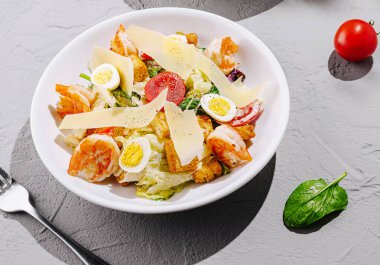 Taze karides, haşlanmış yumurta ve çeşitli sebzelerden oluşan canlı bir salata beyaz bir kasede ustalıkla düzenlenir. Peynir ve otlarla süslenmiş, lezzetli bir deneyime davetiye çıkarıyor..