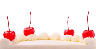 Kremalı pasta güzel bir şekilde çırpılmış krema ve parlak kırmızı kirazlarla süslenir. Tatlı, temiz beyaz bir arkaplan içeren şenlikli bir toplantıda servis edilmeyi bekliyor..