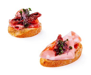 İki lezzetli aperatif taze kızarmış ekmeğin üzerine konmuş taze et dilimleri ve kurutulmuş domatesler sergiliyor. Bu lezzetli ısırıklar toplanmak için mükemmel..