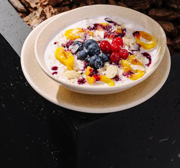 Yoğurtla dolu canlı bir kase mango, yabanmersini ve ahududu gibi çeşitli taze meyvelerle süslenir. Bu lezzetli yemek açık havada, güneşli bir günde..