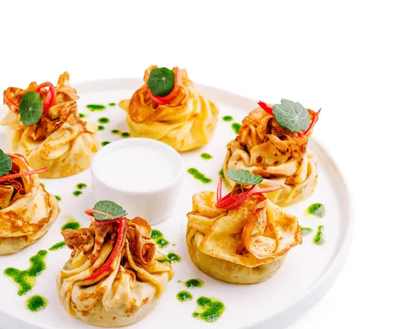 İçi et dolu iştah açıcı gözlemeler, keseye bağlanmış, sosla servis edilmiş, beyaz tabakta otlar, gurme yemekler..