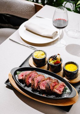 Zarif bir restoran atmosferinde, yanında patates püresi ve sos da dahil olmak üzere çeşitli yönlerde servis edilen güzel bir tabak biftek..