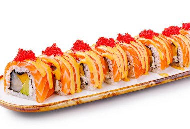 Uzun bir suşi rulosu beyaz bir tabakta güzelce düzenlenir. İçinde balık, baharat sosu ve renklerin ve dokuların karışımından oluşan canlı malzemeler yer alıyor..