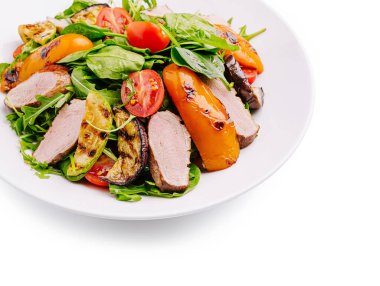 Üzerinde ızgara dolma biber, domates ve dilimlenmiş et bulunan taze roka içeren canlı bir salata. Bu yemek renkli sebzeleri ve yağsız proteini ön plana çıkarıyor. Besleyici bir yemek için mükemmel..