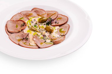 İnce dilimlenmiş soğuk et, kapari ve taze otlarla süslenmiş beyaz bir tabakta zarif bir şekilde düzenlenir. Bir tutam zeytinyağı lezzetleri ve sunumu artırır..