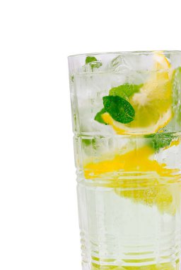 Buz küpleri, taze nane yaprakları ve limon dilimleriyle dolu uzun bir bardak. Bu ferahlatıcı içecek sıcak bir günde serinlemek için mükemmel bir yol sunuyor, canlı renkleri ve dokuları vurguluyor..