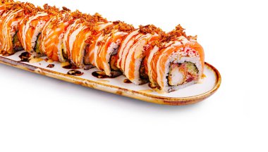 Portakal soslu ve çıtır çıtır çıtır bir suşi rulosu parlak, uzun bir tabakta sergileniyor..