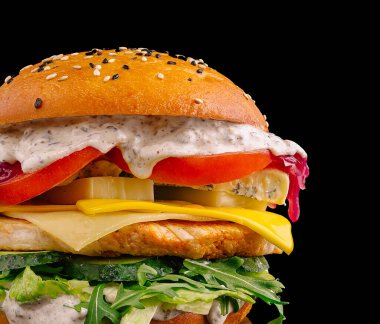 Izgara tavuk, erimiş peynir, taze yeşillikler ve canlı malzemelerle dolu gurme bir hamburger koyu bir arka planda çok güzel duruyor. Lezzetli sos yemeğe zenginlik katıyor..