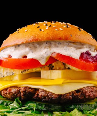 Bir gurme hamburgerin içinde sulu bir köfte, erimiş peynir, taze domates dilimleri ve kremalı sos vardır. Hepsi de kıvırcık kıvırcık salatayla çevrili yumuşak bir susamlı çöreğin içine yerleştirilmiştir..