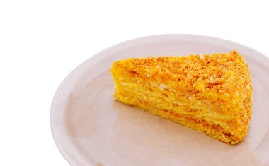 Bir dilim altın kek açık renkli bir tabakta duruyor. Pasta zengin ve nemli, kıtır kıtır bir dokuya sahip, tatlı severler için mükemmel. Günün her saatinde tatlı bir ziyafetin tadını çıkar..