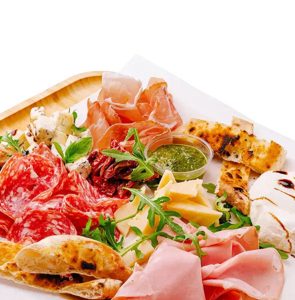 Çok güzel düzenlenmiş bir şarküteri panosunda çeşitli et, peynir ve taze sebzeler sergileniyor. Tabak, toplantılarda veya özel günlerde paylaşmak için mükemmeldir..