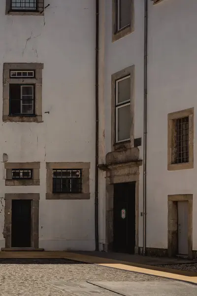 stock image A white building features a black door and windows, set against a road surface. The facade is made of composite material. Its door is made of wood