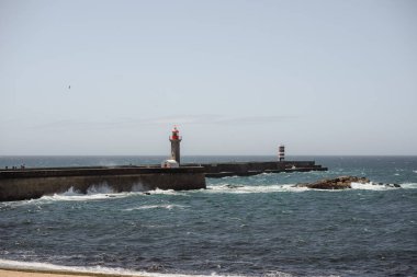 Uçsuz bucaksız okyanusta, sonsuz su, ufuk ve gökyüzüne tepeden bakan ıssız bir deniz feneri, denizlerdeki gemiler için bir yol gösterici görevi görüyor.