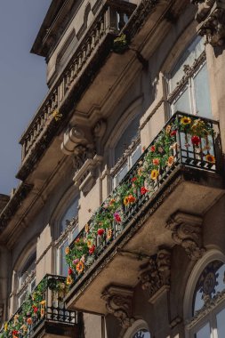 Renkli çiçeklerle süslenmiş güzel bir balkon binanın yan tarafını güzelleştirir ve şehir manzarasına cazibesini katar.