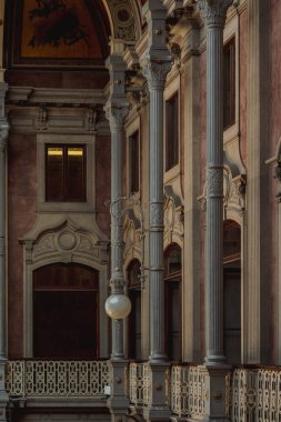 Binanın ön cephesinde ortaçağ mimarisi ve sanatsal oymaları yansıtan asılı bir ışıkla simetrik sütunlar ve bir balkon bulunur.