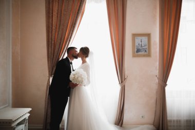 Güzel, genç bir çift ellerinde çiçeklerle poz veriyorlar..