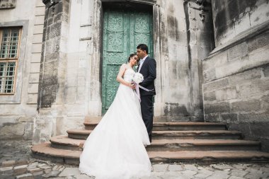 Muhteşem mutlu çift birbirine yakın duruyor ve eski şehir geçmişine, düğün fotoğrafına, Avrupa şehrine, Lviv 'de düğün gününe bakıyor..