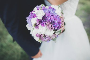 Gelin çiçekli büyük ve güzel bir düğün buketi tutuyor..