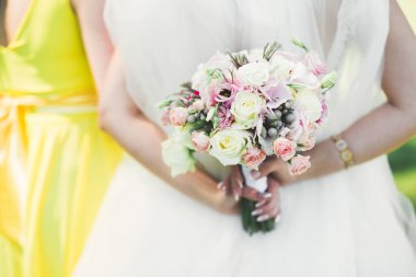 Gelin çiçekli büyük ve güzel bir düğün buketi tutuyor..