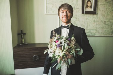 Yaka çiçeğiyle poz veren mutlu yakışıklı damat..