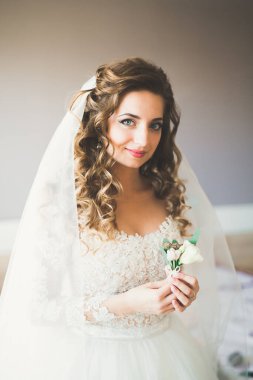 Cüppeli muhteşem gelin bir odada düğün töreni için poz veriyor ve hazırlanıyor..