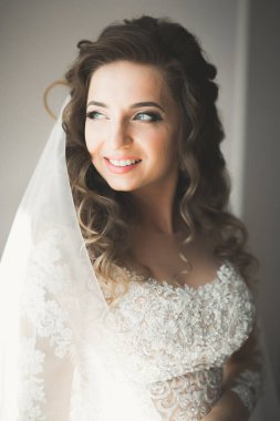 Cüppeli muhteşem gelin bir odada düğün töreni için poz veriyor ve hazırlanıyor..