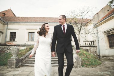 Güzel, romantik bir düğün. Yeni evliler. Eski kalenin yakınlarında sarılıyorlar..