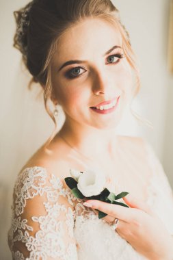 Cüppeli muhteşem gelin bir odada düğün töreni için poz veriyor ve hazırlanıyor..