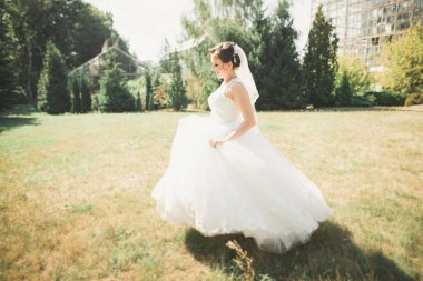 Parkta poz veren zarif beyaz elbiseli güzel gelin..