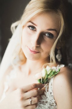 Cüppeli muhteşem gelin bir odada düğün töreni için poz veriyor ve hazırlanıyor..