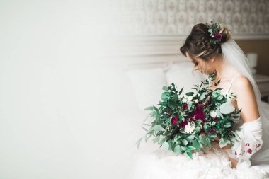 Cüppeli muhteşem gelin bir odada düğün töreni için poz veriyor ve hazırlanıyor..