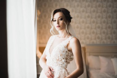 Cüppeli muhteşem gelin bir odada düğün töreni için poz veriyor ve hazırlanıyor..