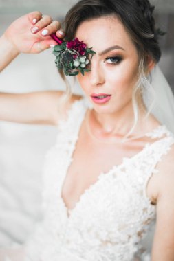 Cüppeli muhteşem gelin bir odada düğün töreni için poz veriyor ve hazırlanıyor..