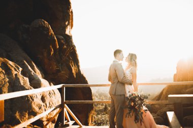 Güzel dağlarda poz veren mutlu bir düğün çifti..