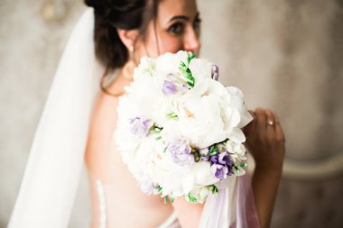 Gelin çiçekli büyük ve güzel bir düğün buketi tutuyor..