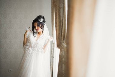 Cüppeli muhteşem gelin bir odada düğün töreni için poz veriyor ve hazırlanıyor..