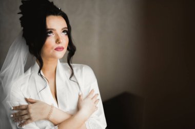 Cüppeli muhteşem gelin bir odada düğün töreni için poz veriyor ve hazırlanıyor..