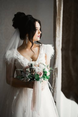 Çekici gelinin portresi, uzun saçlı, büyük buketli poz veren..