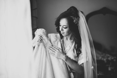 Cüppeli muhteşem gelin bir odada düğün töreni için poz veriyor ve hazırlanıyor..