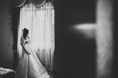 Cüppeli muhteşem gelin bir odada düğün töreni için poz veriyor ve hazırlanıyor..