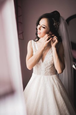 Cüppeli muhteşem gelin bir odada düğün töreni için poz veriyor ve hazırlanıyor..