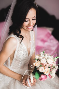 Cüppeli muhteşem gelin bir odada düğün töreni için poz veriyor ve hazırlanıyor..