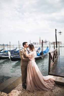 Doğadaki düğün çifti birbirine sarılıyor. Beyaz elbiseli güzel bir kız. Takım elbiseli adam. Venedik, İtalya.