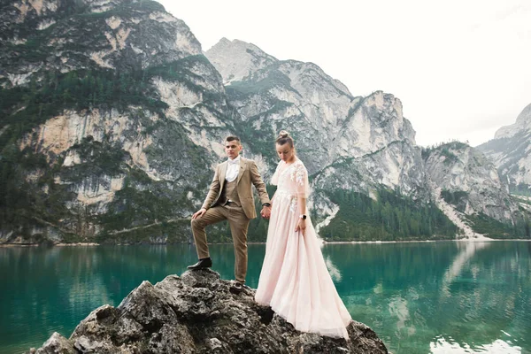 Young couple near lake Karersee, Italy. Holding hands at the stone at lake.