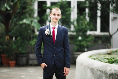 Yaka çiçeğiyle poz veren mutlu yakışıklı damat..