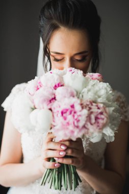 Gelin çiçekli büyük ve güzel bir düğün buketi tutuyor..
