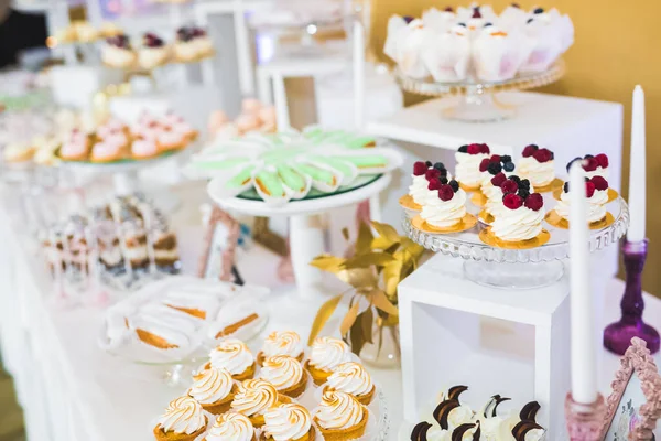 Delicious sweets on wedding candy buffet with desserts, cupcakes.