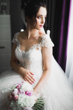 Çekici gelinin portresi, uzun saçlı, büyük buketli poz veren..