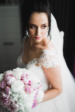 Çekici gelinin portresi, uzun saçlı, büyük buketli poz veren..